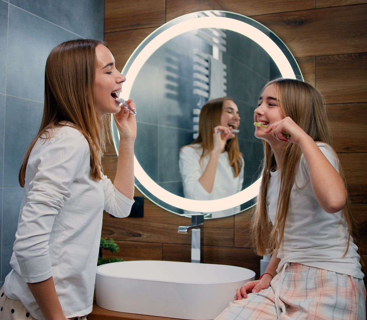 Family Dental Care for Teens, Dentist Prescott AZ Two teenage girls brushing their teeth together at a bathroom mirror