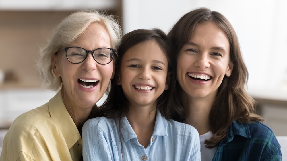 Three generations of women, a grandmother, mother, and young daughter, laughing together, representing the multi-generational family dentistry care at Prescott Dental Arts in Prescott, AZ