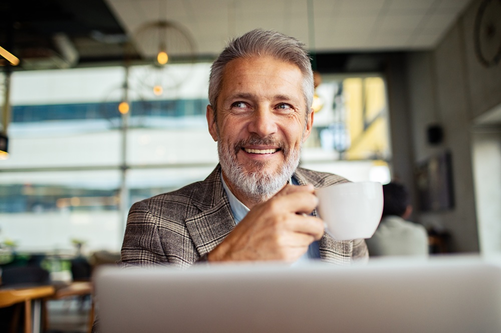 Natural-Looking Porcelain Crowns and Veneers, Dentist Prescott AZ Middle-aged man smiling confidently while enjoying coffee, representing the natural look and durability of porcelain crowns and veneers at Prescott Dental Arts in Prescott, AZ