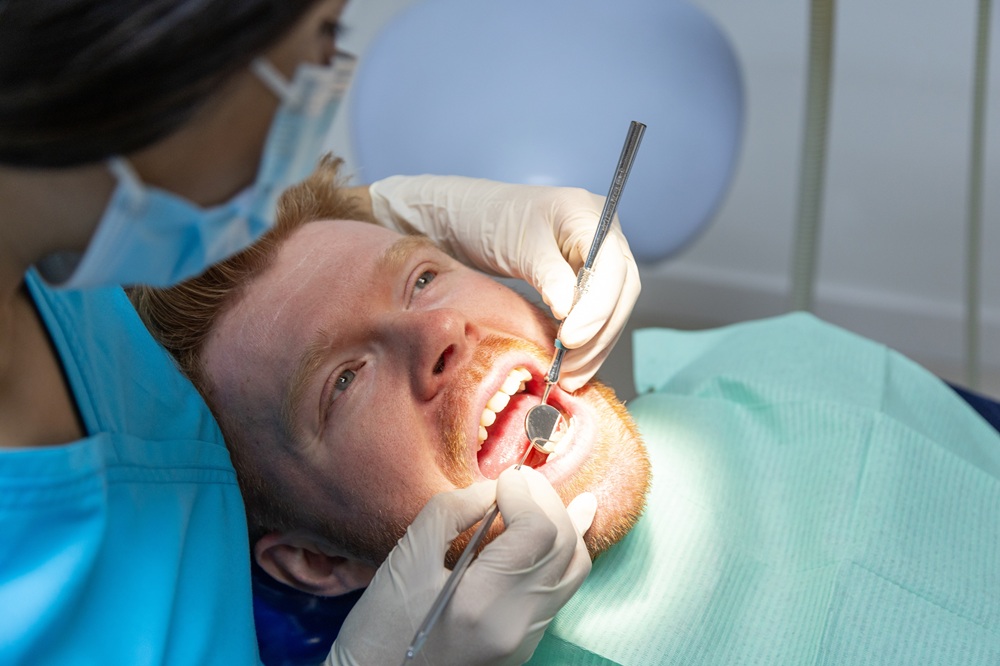 Male patient undergoing a dental examination at Prescott Dental Arts in Prescott, AZ, with a dental hygienist using a mirror and explorer tool